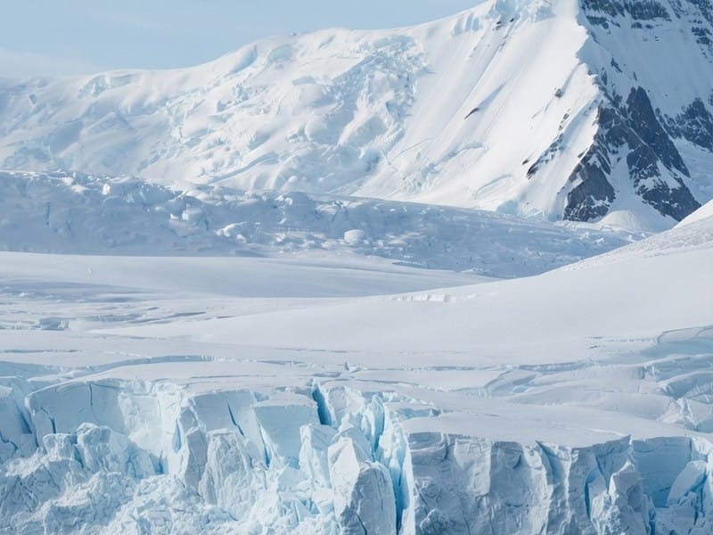 A snow-covered mountain landscape with cracked glaciers and icy cliffs.