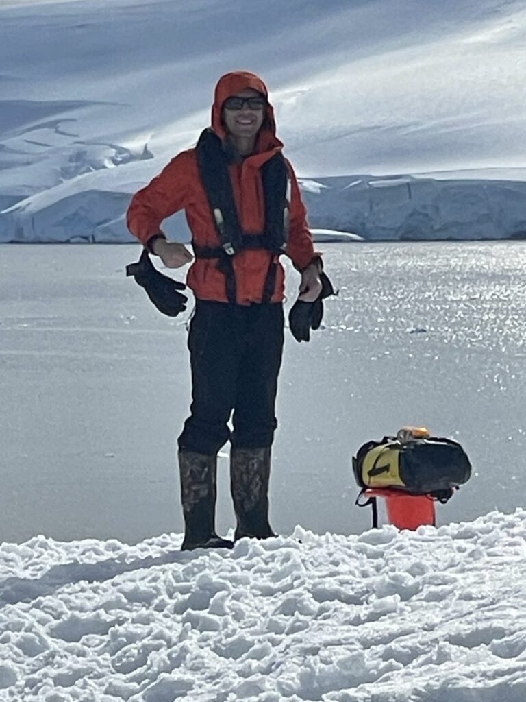 John Arrow standing on the ice in Antarctica in a red expedition jacket and life vest